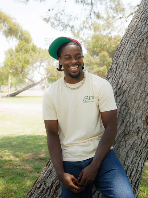 DK in a cream tee against a tree
