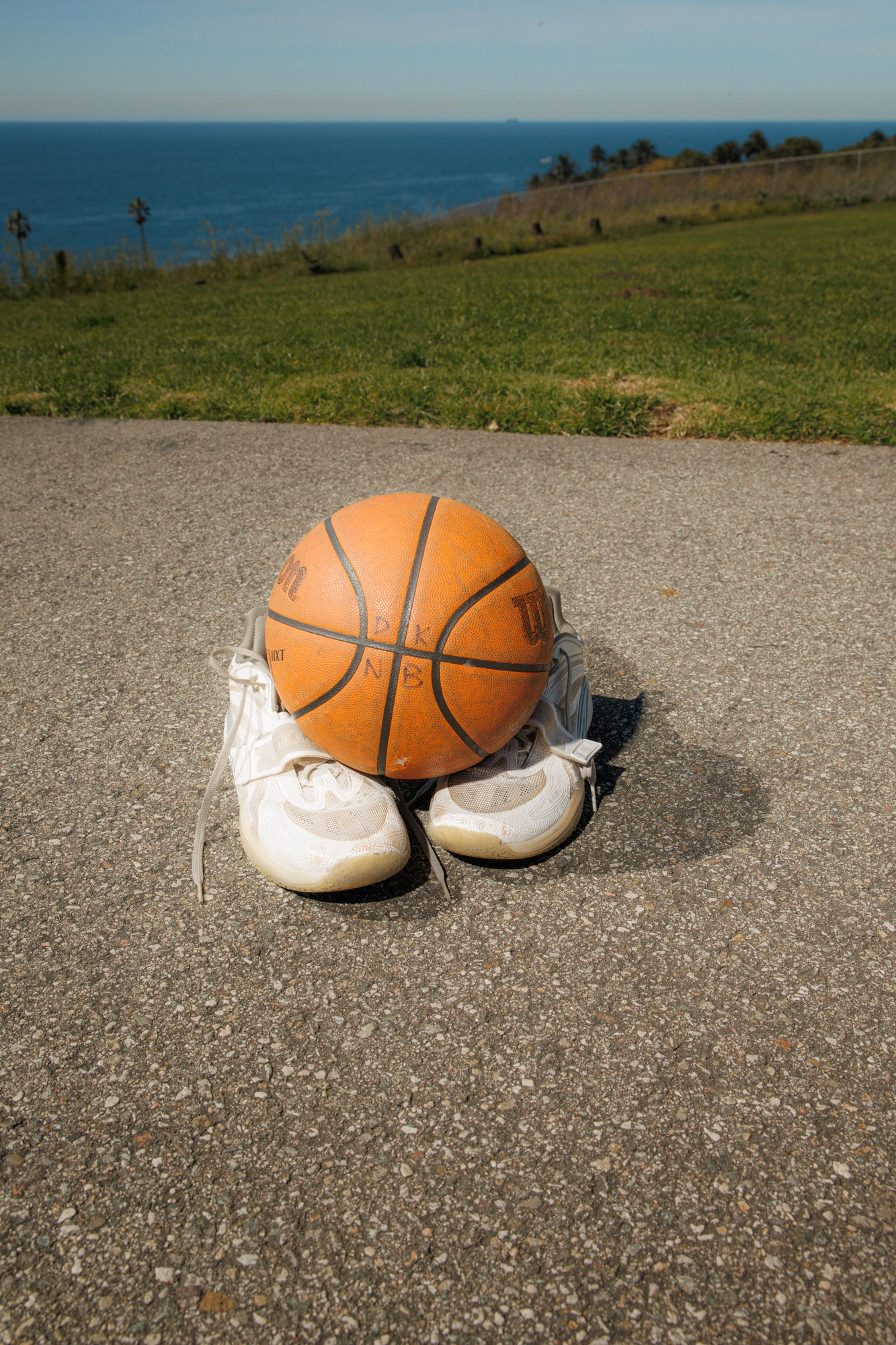 Sneakers and a basketball on the court, no one in frame